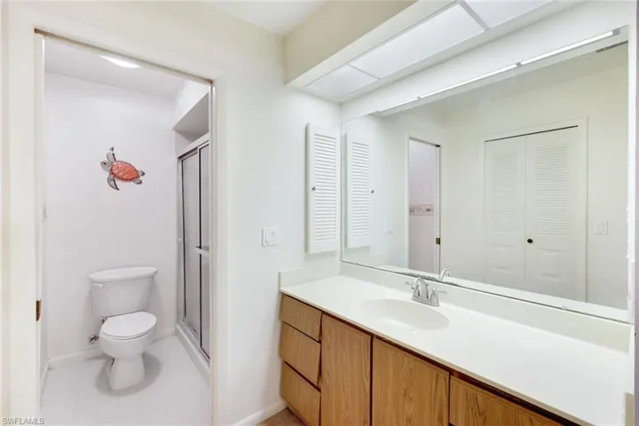 Bathroom featuring toilet, vanity, and a shower with shower door