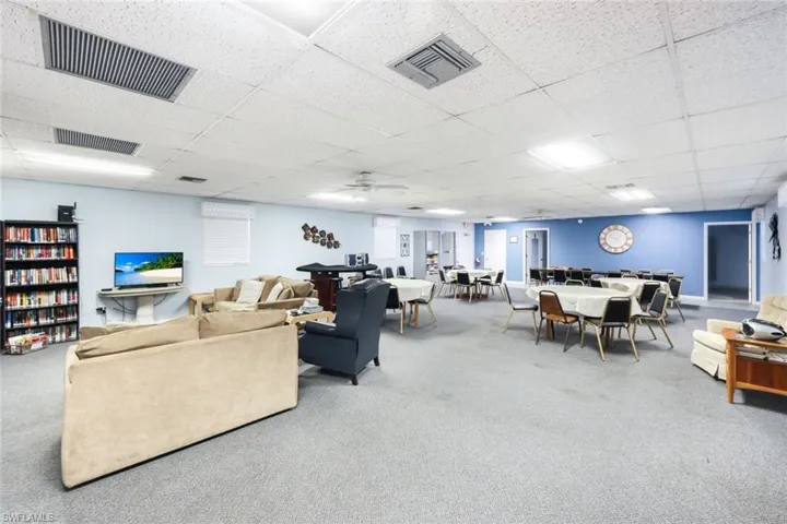 Living room featuring carpet flooring, a paneled ceiling, and ceiling fan