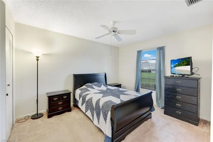 Carpeted bedroom with a textured ceiling, ceiling fan, and a closet