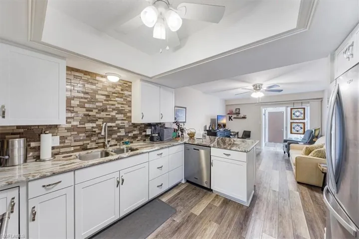 Kitchen featuring stainless steel appliances, ceiling fan, a peninsula, a raised ceiling, and tasteful backsplash