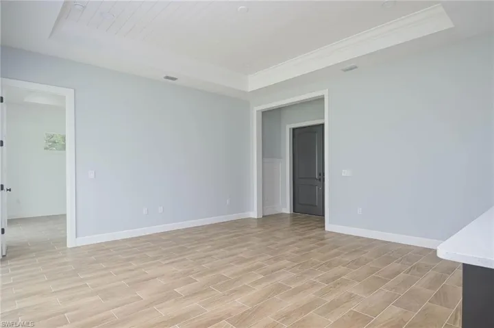Spare room featuring light wood-type flooring and a tray ceiling