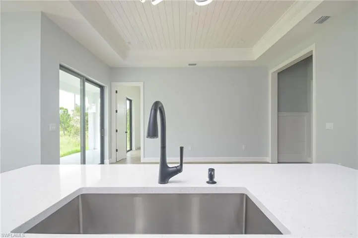 Kitchen featuring sink, light stone counters, and a tray ceiling