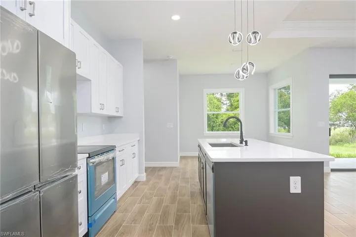 Kitchen featuring decorative light fixtures, stainless steel appliances, sink, light hardwood / wood-style flooring, and a kitchen island with sink