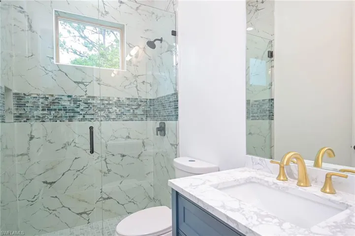 Bathroom featuring vanity, a shower with shower door, and toilet