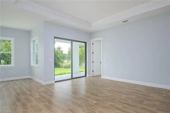 Empty room with light wood-type flooring and a tray ceiling