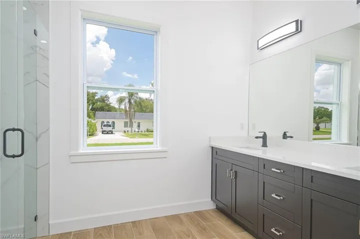 Bathroom with an enclosed shower, a healthy amount of sunlight, hardwood / wood-style floors, and double vanity