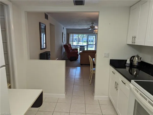 Kitchen with white cabinetry, open floor plan, light tile patterned floors, and a ceiling fan