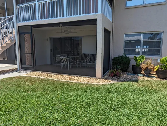Entrance to property featuring a ceiling fan, stucco siding, and a yard