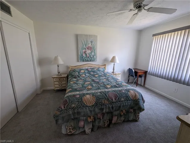 Carpeted bedroom featuring a textured ceiling and ceiling fan