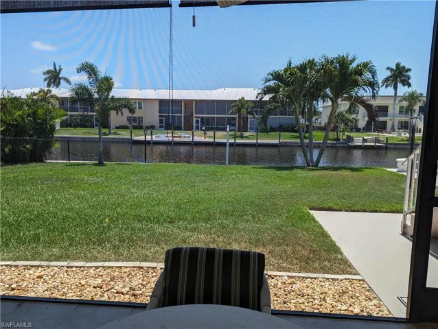 View of grassy yard with a water view and a sunroom