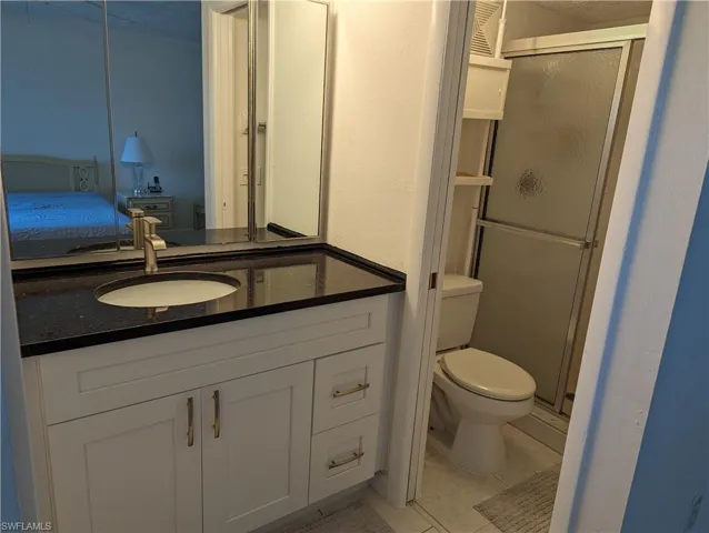 Ensuite bathroom with vanity, a stall shower, and light tile patterned floors