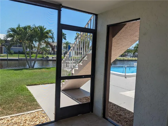 Doorway to outside featuring plenty of natural light, a textured wall, a water view, and tile patterned flooring