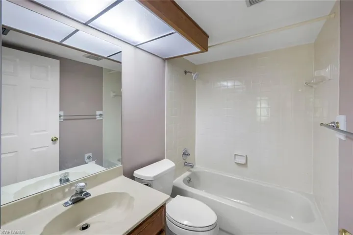 Bathroom featuring a built-in bathtub with shower, white tile surround, and an integrated toilet