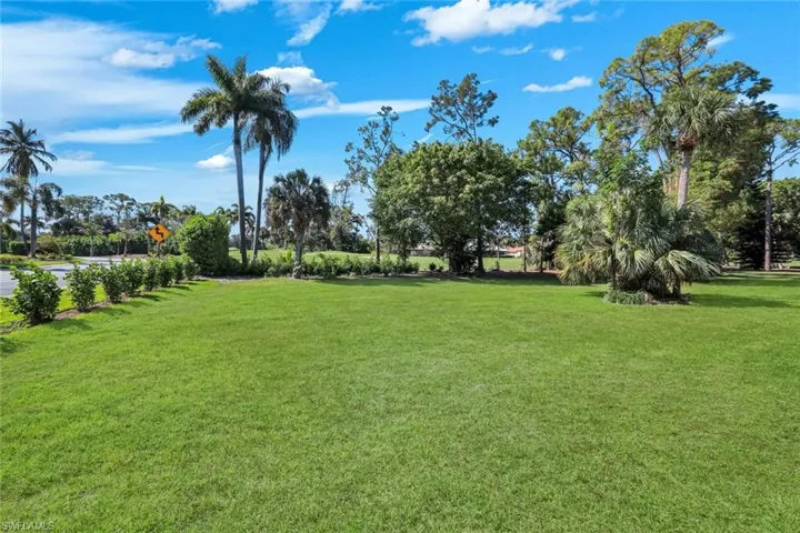 Expansive green lawn with established landscaping and mature palm trees