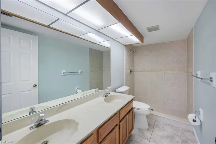 Bathroom featuring a dual-sink vanity with wood cabinetry, a light-toned countertop, and chrome fixtures