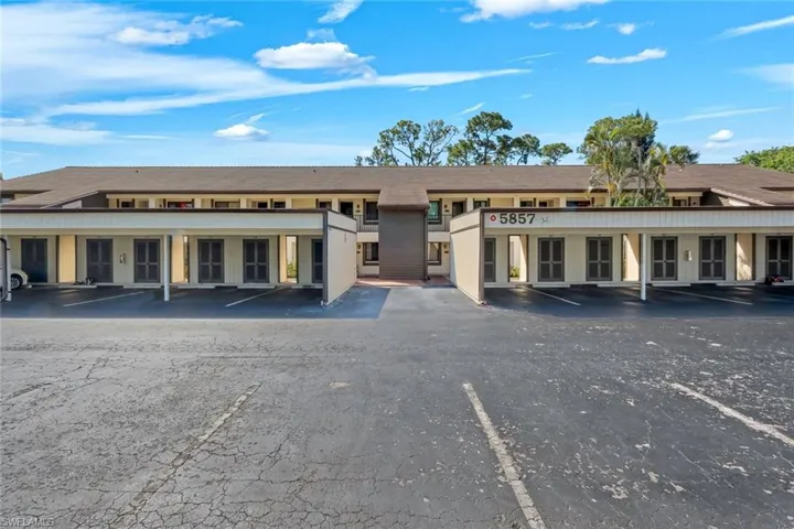 Multi-level condominium building featuring a brown shingle roof and covered parking spaces