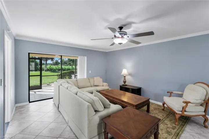 Expansive living area featuring tile flooring, crown molding, and a ceiling fan with integrated lighting