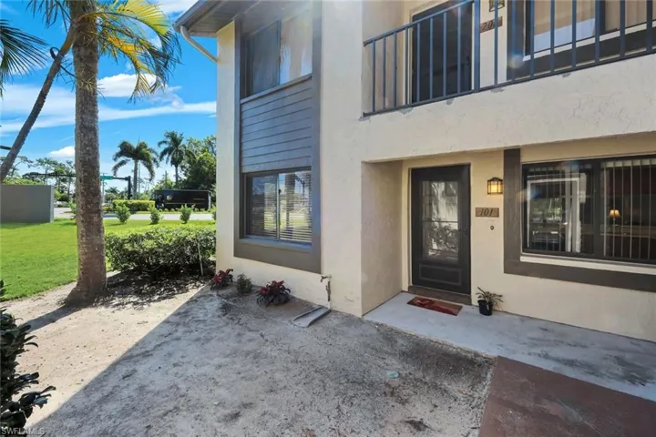 Entry-level unit featuring a glass-paneled front door, exterior lighting, and a private upper-level balcony