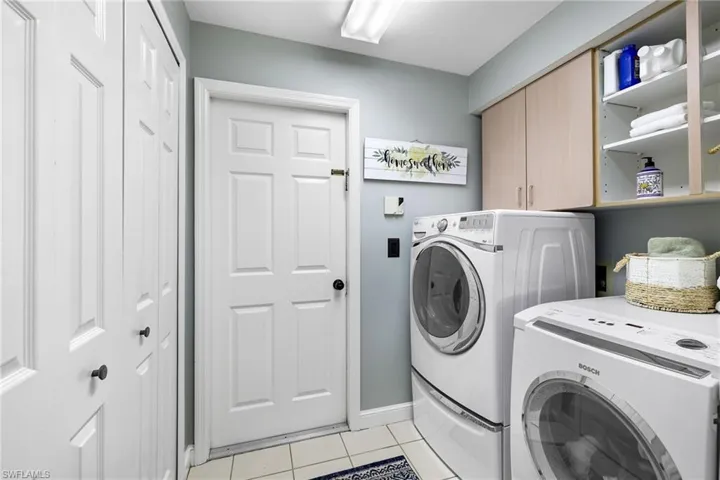 Laundry area, washer and dryer included, light tile floors, closet and built in cabinetry, door to garage
