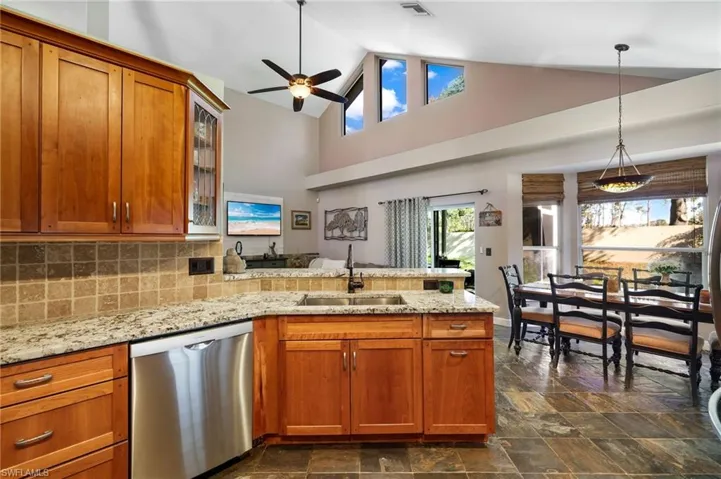 Kitchen with pendant lighting, dishwasher, high vaulted ceiling, sink, and ceiling fan