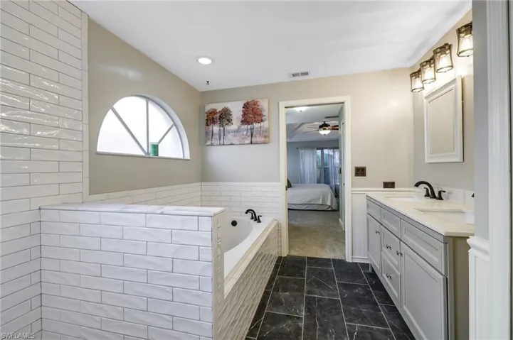 Ground Floor Bathroom with tiled walk in shower, large garden tub, separate wood cabinetry vanities and mirrors