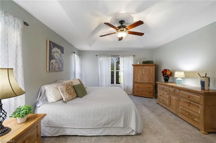 Ground floor main bedroom suite featuring tray ceiling and fan