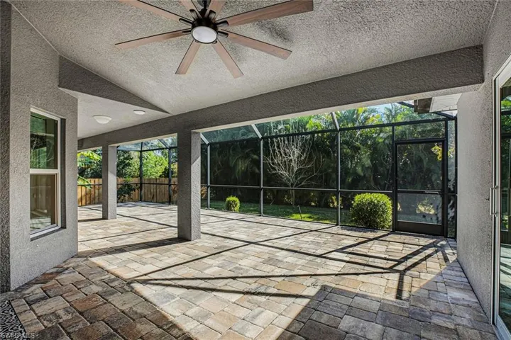 Unfurnished sunroom featuring a patio, a ceiling fan, and vaulted ceiling