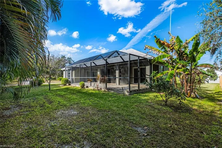 Back of property with a lanai, a sunroom, and a yard