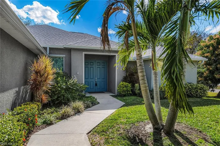 Doorway to property featuring roof with shingles, stucco siding, and a yard
