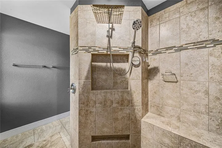 Full bathroom with tiled shower and a textured wall