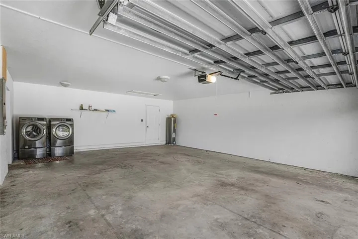 Garage featuring washing machine and dryer, water heater, and a garage door opener