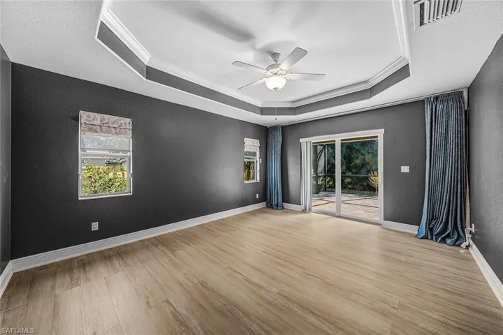 Spare room with ornamental molding, light wood-style flooring, a textured wall, a ceiling fan, and plenty of natural light