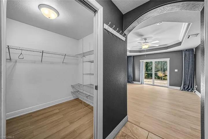 Walk in closet with light wood-style flooring, a ceiling fan, and a raised ceiling