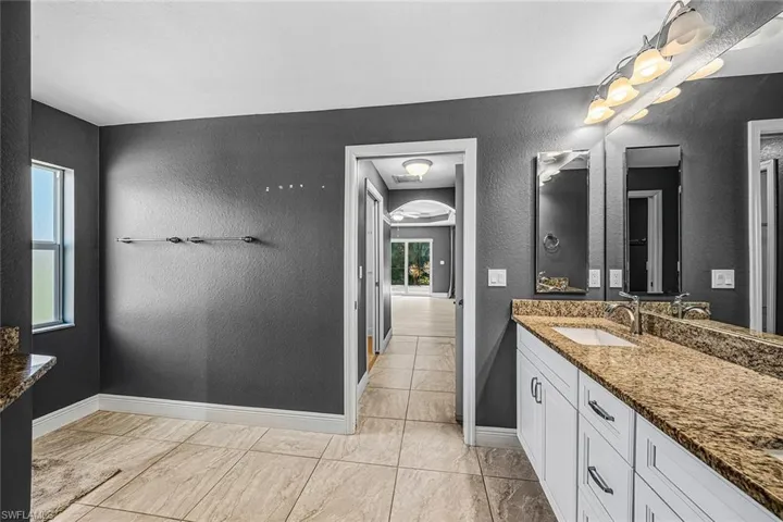 Full bathroom featuring vanity and a textured wall
