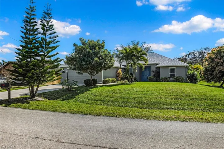 Obstructed view of property with an attached garage, stucco siding, concrete driveway, and a front lawn