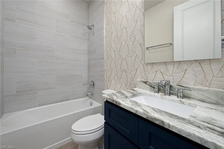 Full bathroom with vanity, toilet, tiled shower / bath, and backsplash