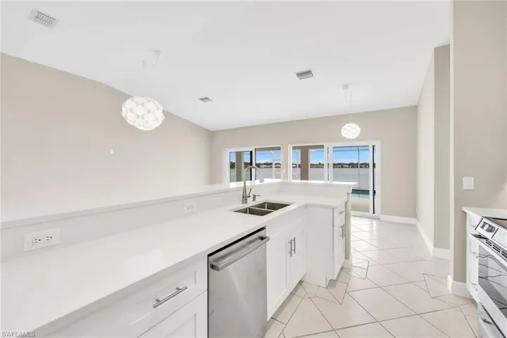 Kitchen with stainless steel appliances, decorative light fixtures, white cabinets, light tile patterned floors, and light stone countertops