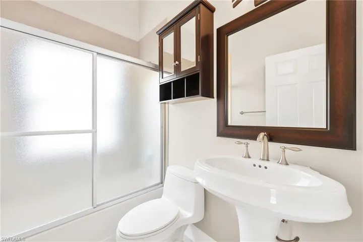 Bathroom featuring bath / shower combo with glass door and toilet