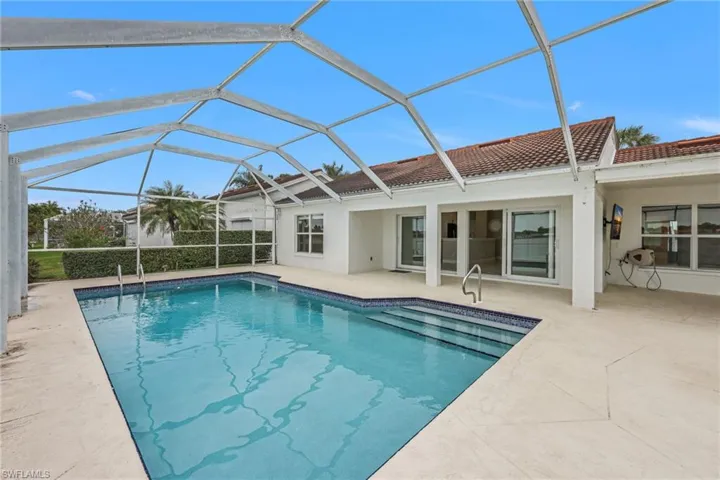 Swimming pool with a sunroom, a patio area, and glass enclosure