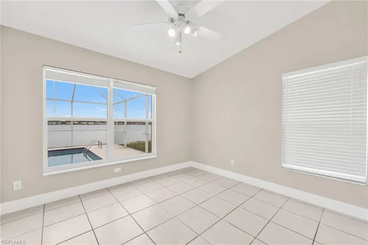 Unfurnished room with vaulted ceiling, a ceiling fan, and light tile patterned floors