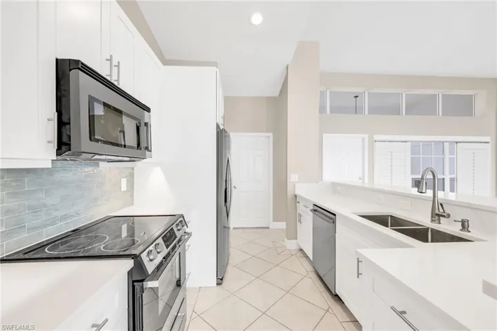 Kitchen featuring appliances with stainless steel finishes, white cabinets, tasteful backsplash, light tile patterned flooring, and recessed lighting