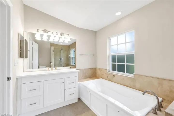 Bathroom featuring a bath, vanity, a stall shower, and light tile patterned floors