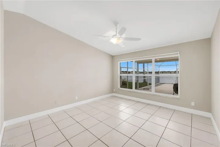 Empty room with lofted ceiling, a ceiling fan, and light tile patterned floors