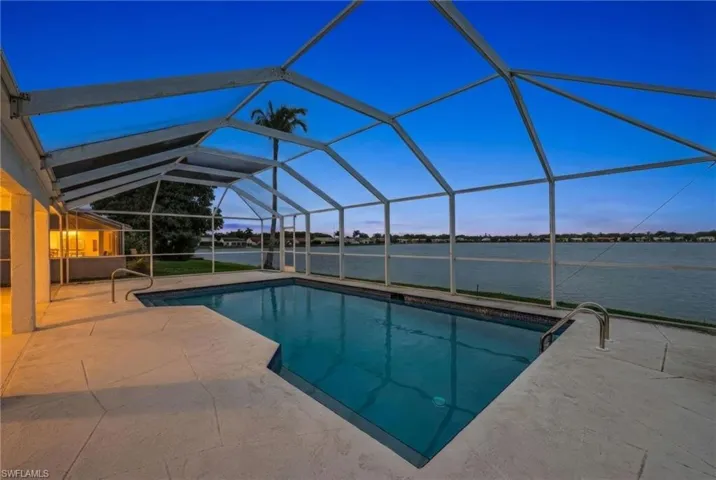 Swimming pool featuring a sunroom, glass enclosure, a water view, and a patio