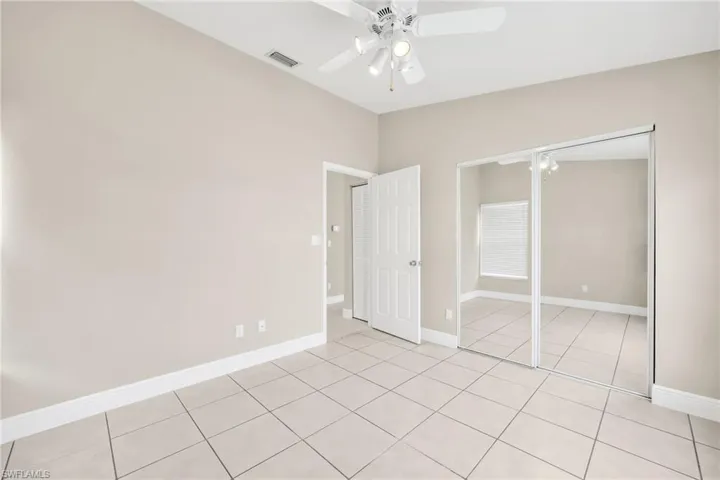 Unfurnished bedroom featuring ceiling fan, light tile patterned floors, and a closet