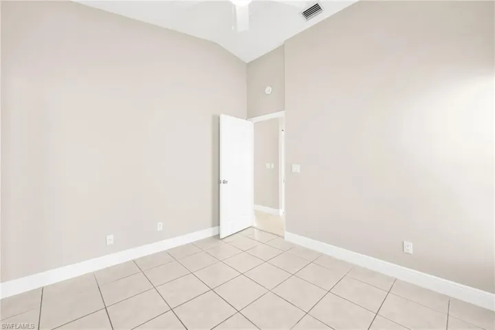 Spare room with lofted ceiling, light tile patterned flooring, and a ceiling fan