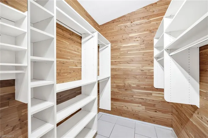 Walk in closet featuring light tile patterned floors and vaulted ceiling