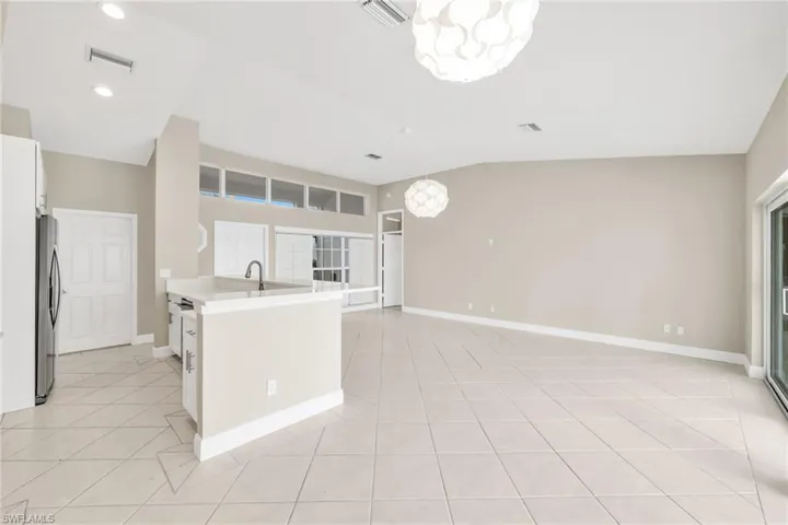 Kitchen with a chandelier, freestanding refrigerator, white cabinetry, recessed lighting, and light tile patterned flooring