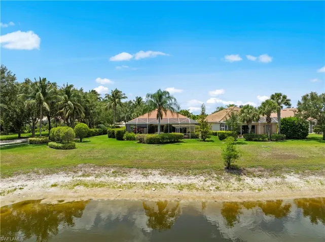 Back of house with a water view and a lawn