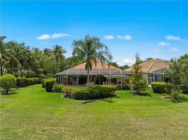 Back of property featuring a lawn and glass enclosure